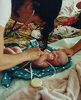 midwife listening to newborn's heartbeat